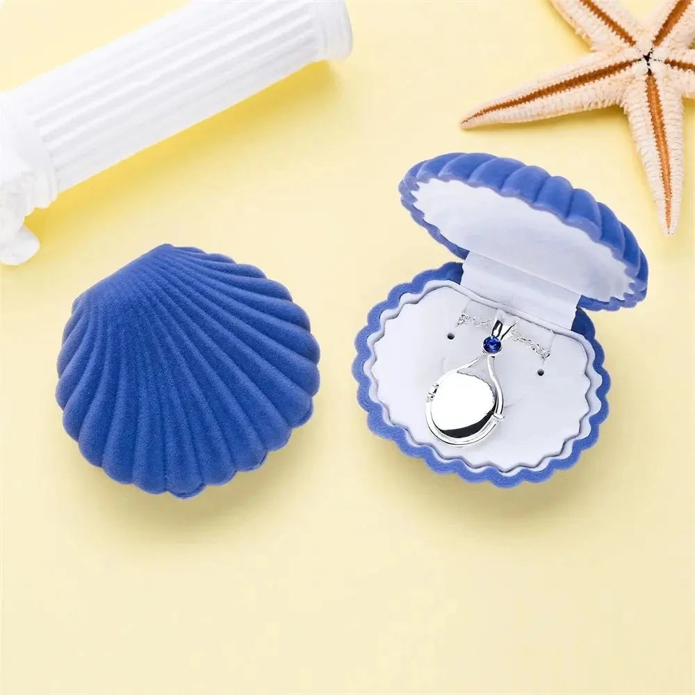 Blue shell-shaped jewelry box with a necklace inside on a yellow background