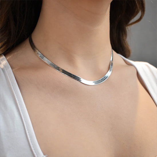 silver necklace worn by a person against a neutral background