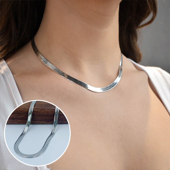 Silver necklace worn by a person with a close-up inset showing the texture of the chain.